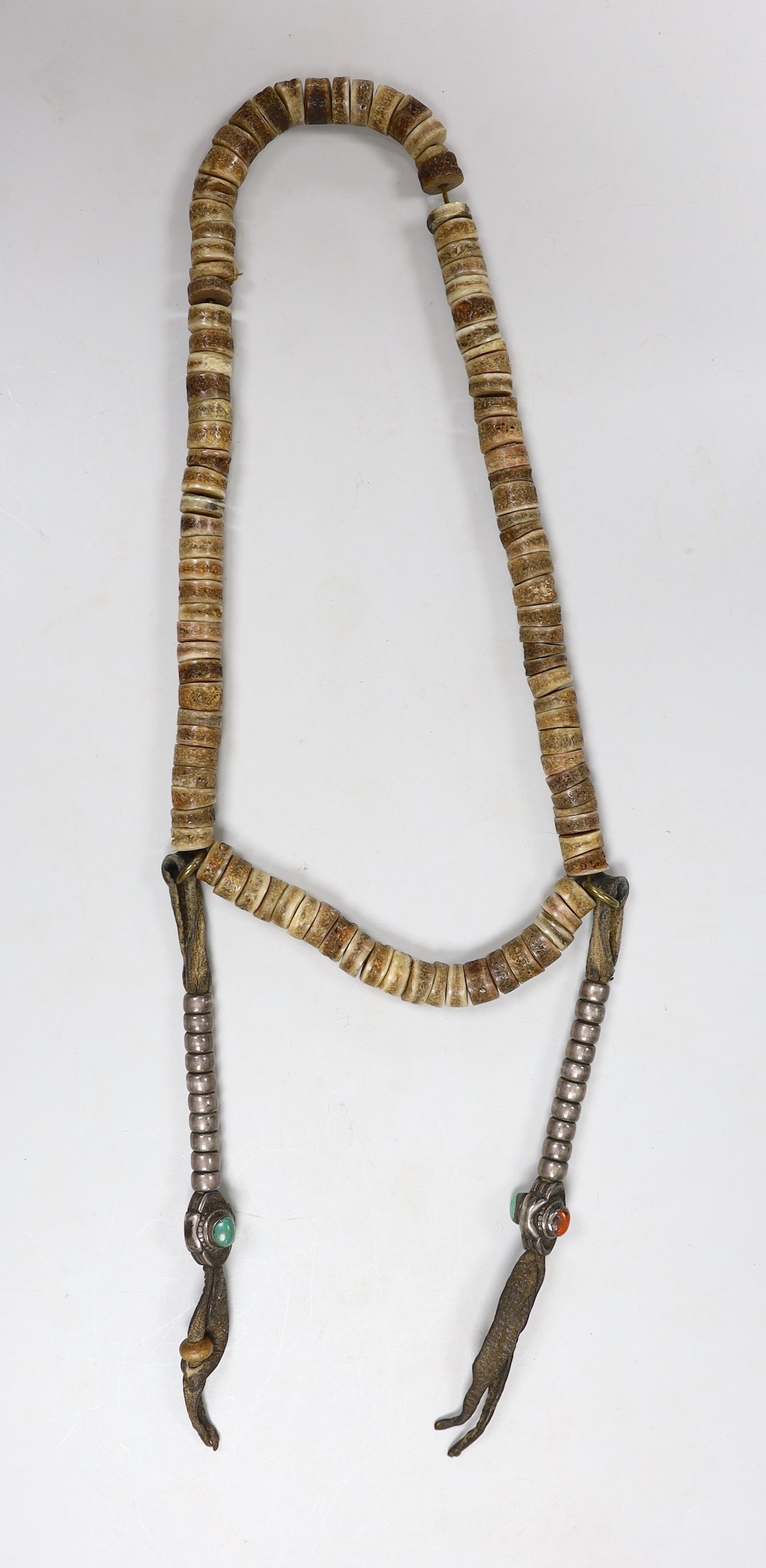 A Tibetan bone, coral and turquoise mounted necklace and a brocade mounted panel